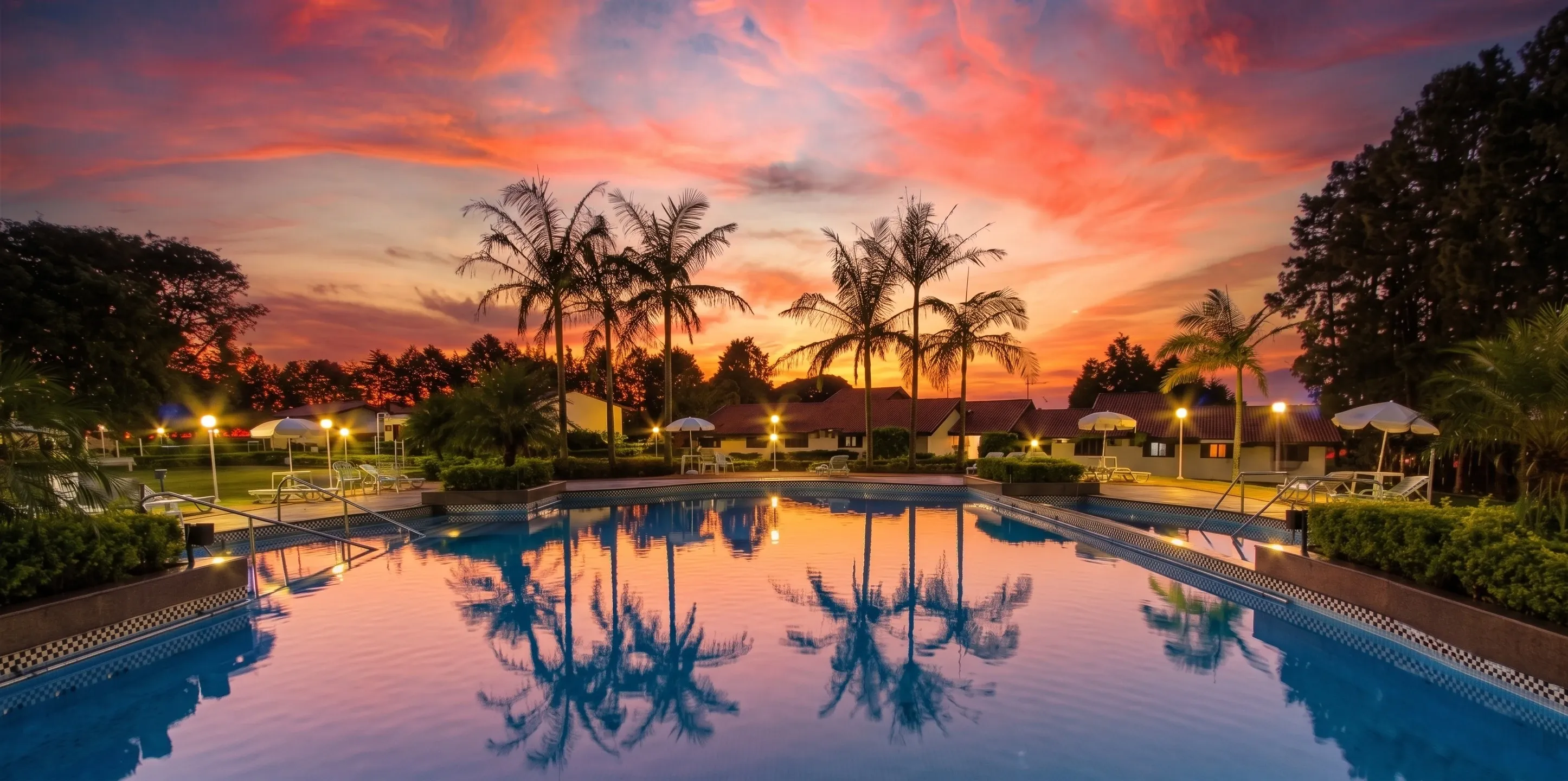 Piscina do Spa Sorocaba ao pôr do sol, cercada por palmeiras